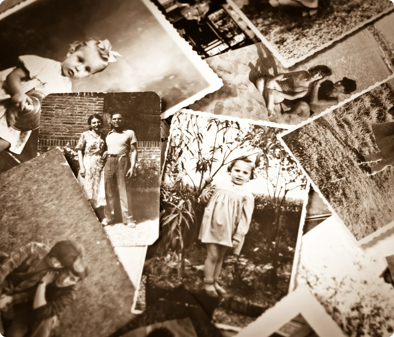 A collection of old black-and-white family photographs scattered on a surface.